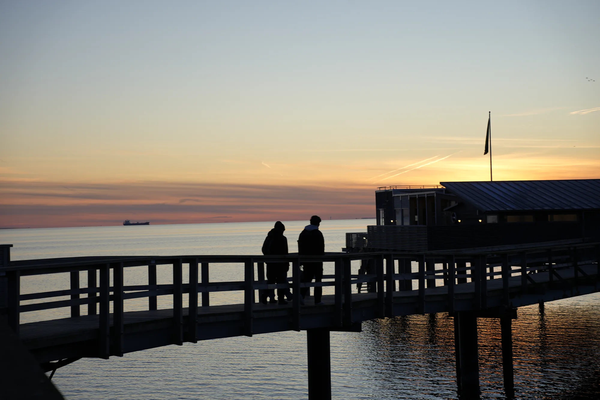 Figures walking a long pier at blue hour in Skåne, Sweden
