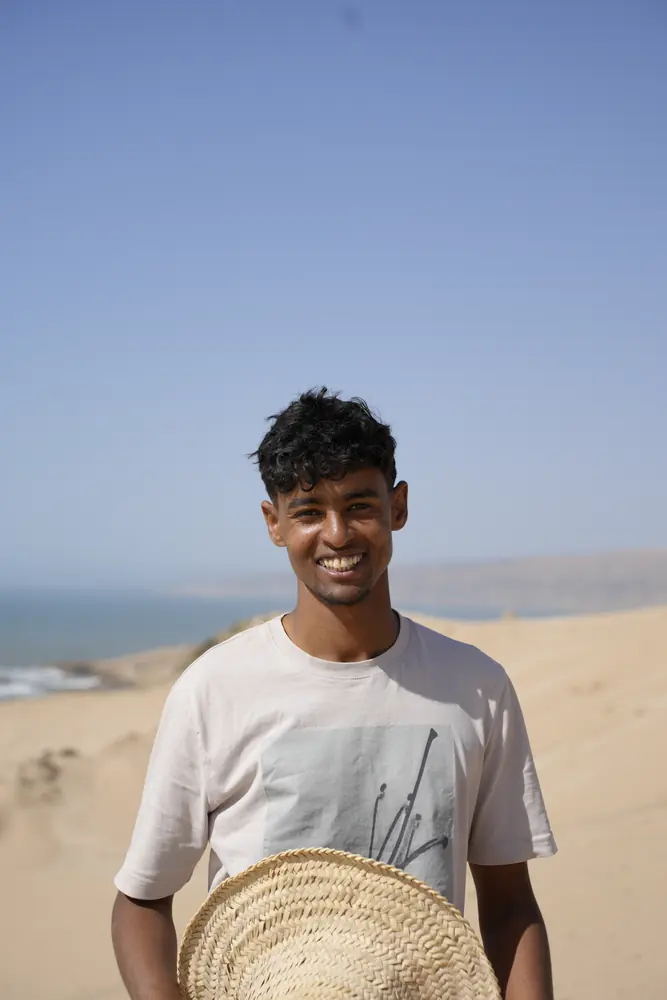 Portrait of a young man holding a straw hat by the sea
