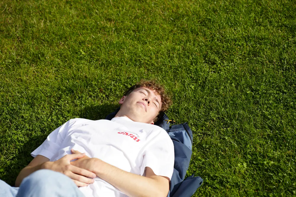 A person lying on grass in the afternoon sun