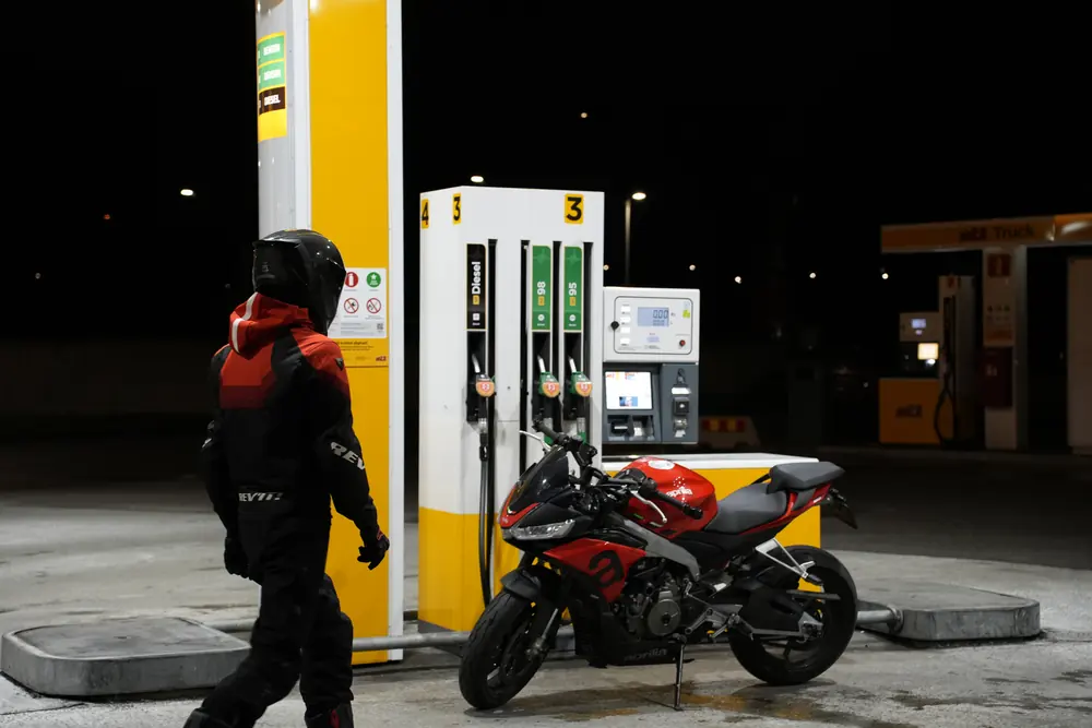 Motorcyclist under the lights of a petrol station at night